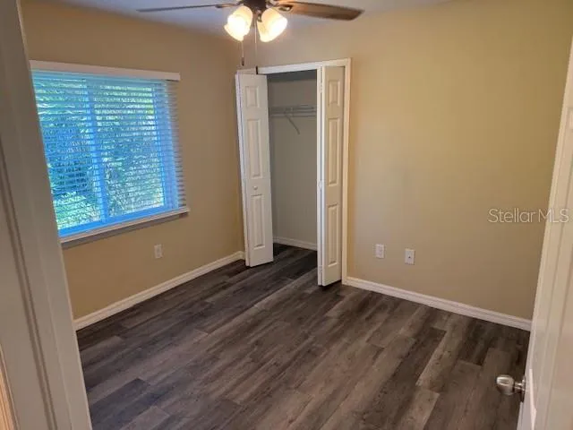 an empty room with wooden floor fan and windows