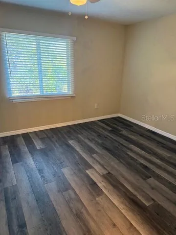 a view of an empty room with wooden floor and a window