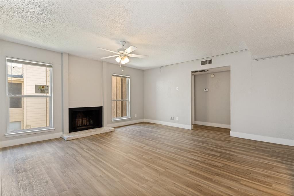 5522 Boca Raton Boulevard, Unit 404 Fort Worth, TX 76112 - Photo 5 of 12 Spacious living area featuring wood-finish flooring, a fireplace with a light-toned hearth, and two windows providing natural illumination