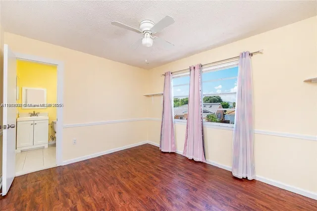 an empty room with wooden floor and ceiling fan