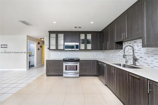 a large kitchen with stainless steel appliances wooden cabinets a stove and a sink