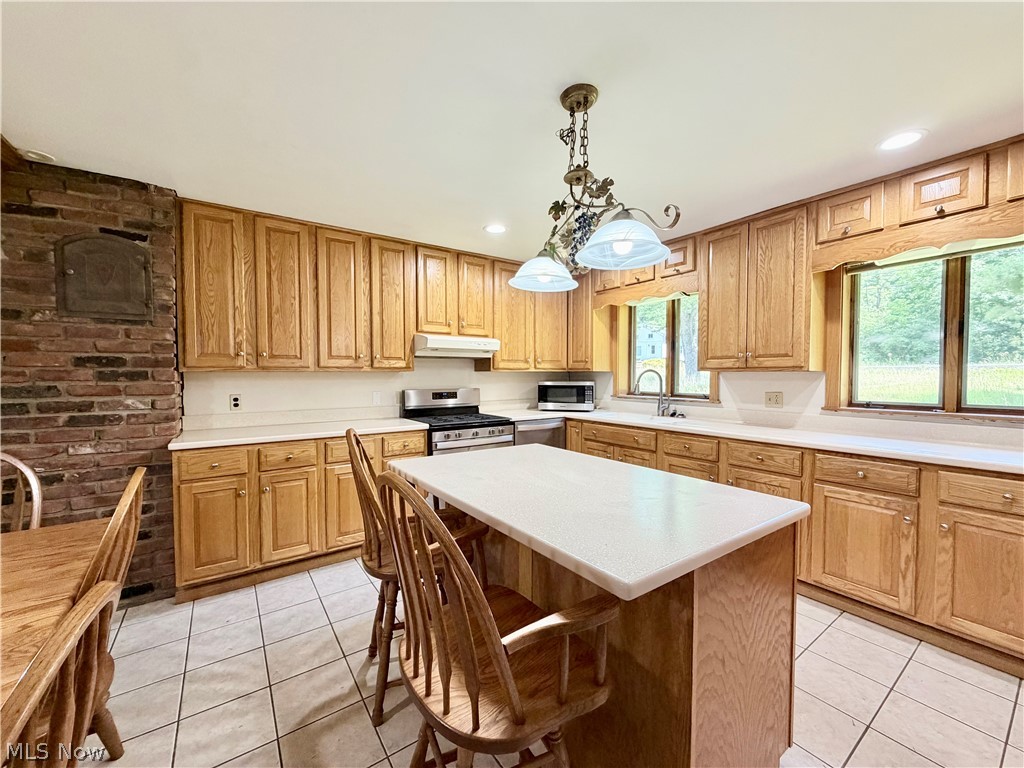 12590 Rockhaven Road Chesterland, OH 44026 - Photo 8 of 25 Kitchen featuring extensive wood cabinetry, light-toned countertops, tile flooring, and a central island with seating