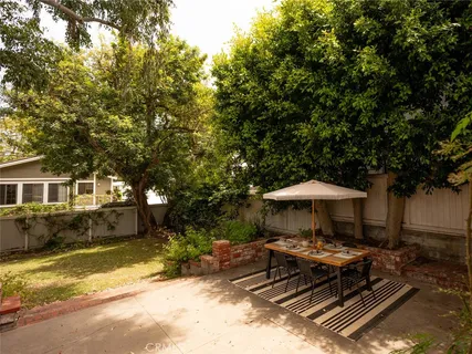 a view of a table and chairs under an umbrella in backyard