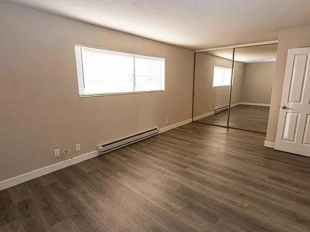 an empty room with wooden floor and windows
