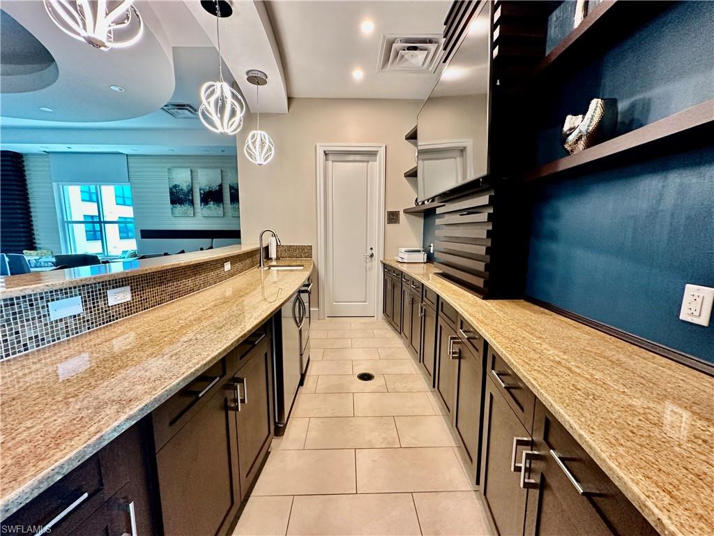 9115 Strada Place, Unit 5211 Naples, FL 34108 - Photo 23 of 30 Kitchen with backsplash, decorative light fixtures, light stone counters, sink, and light tile patterned flooring