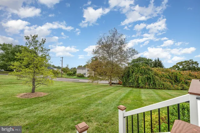 a view of a white house with a big yard plants and large trees