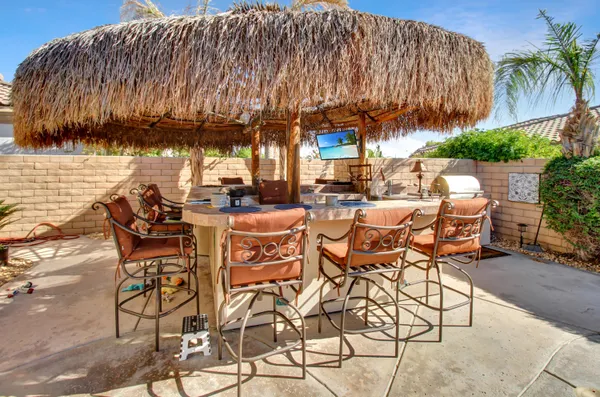 a view of a patio with table and chairs under an umbrella with a barbeque
