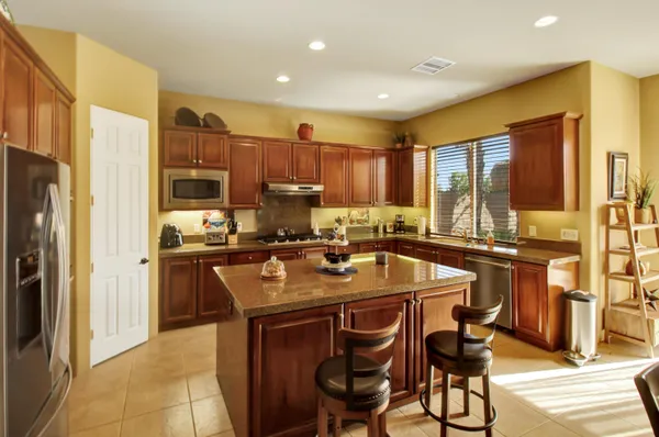 a kitchen with stainless steel appliances granite countertop a table chairs sink refrigerator and cabinets