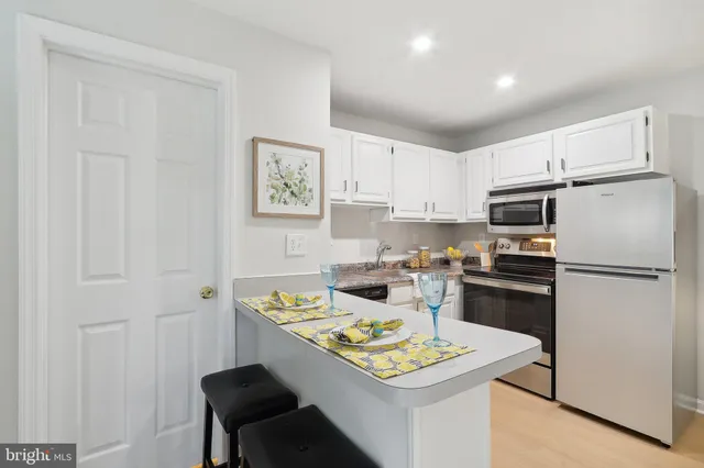 a kitchen with a refrigerator a stove a sink dishwasher and white cabinets with wooden floor