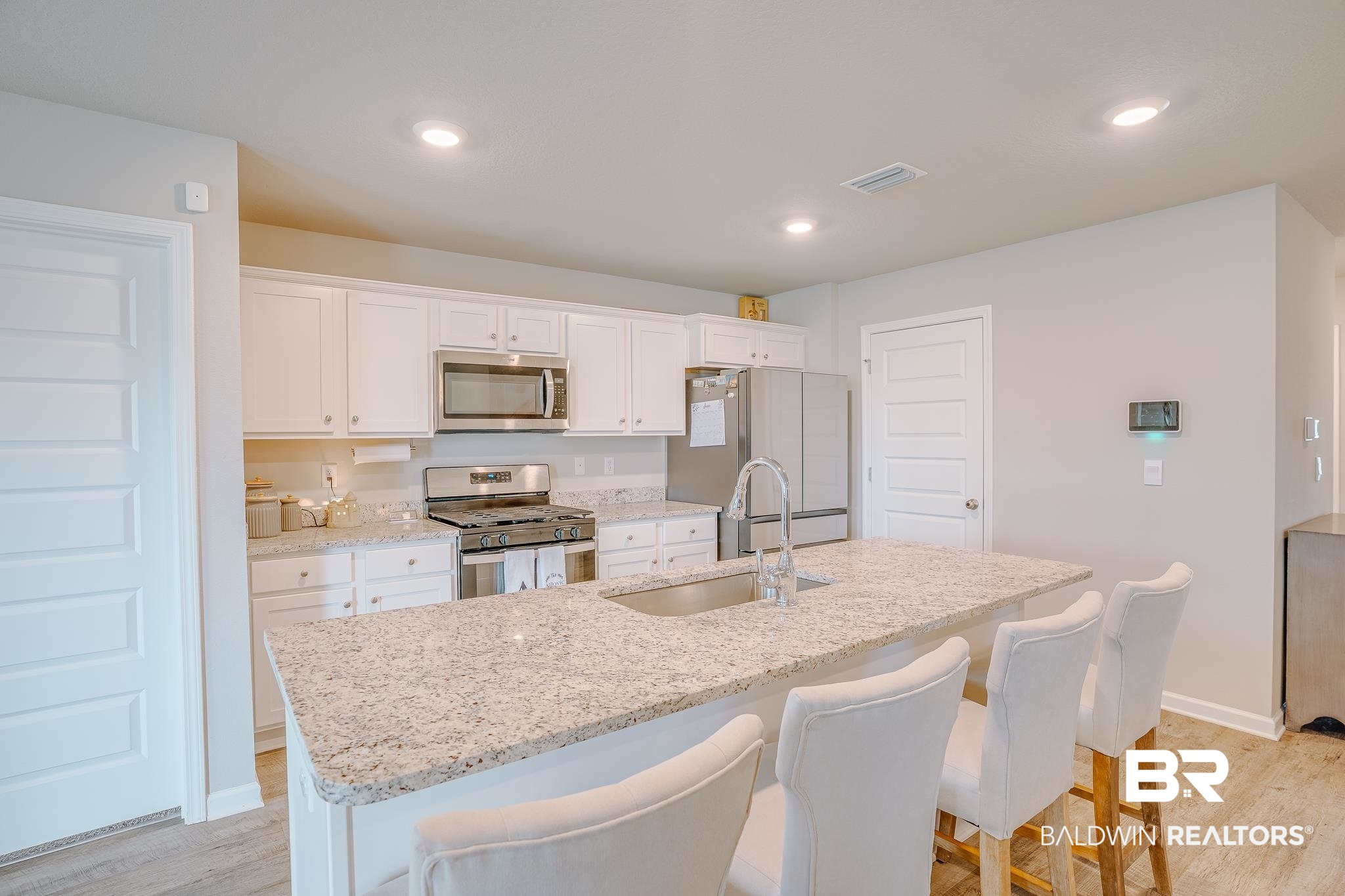 8242 Sycamore Way Semmes, AL 36575 - Photo 13 of 43 Kitchen with appliances with stainless steel finishes, an island with sink, white cabinets, light wood-style floors, and recessed lighting