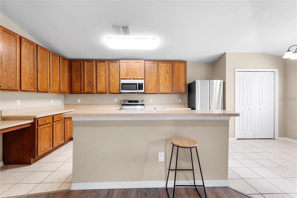 3483 Beaumont Loop Spring Hill, FL 34609 - Photo 4 of 14 a kitchen with stainless steel appliances granite countertop a sink a stove a refrigerator cabinets and a dining table