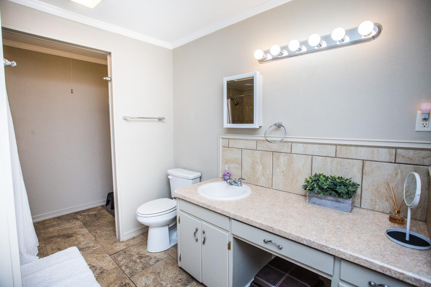 2418 23rd Street Lubbock, TX 79411 - Photo 14 of 17 a bathroom with a granite countertop sink a toilet and mirror