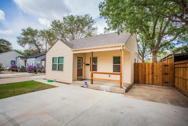 a view of a house with a yard and large tree