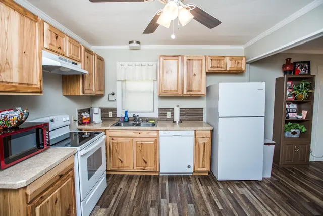 a kitchen with a refrigerator a stove a sink dishwasher and white cabinets with wooden floor