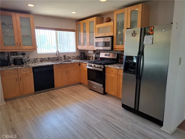 a kitchen with stainless steel appliances granite countertop a refrigerator a sink dishwasher a stove with wooden floors