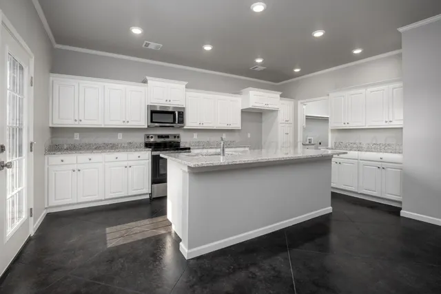 a kitchen with stainless steel appliances granite countertop a stove top oven a sink and white cabinets