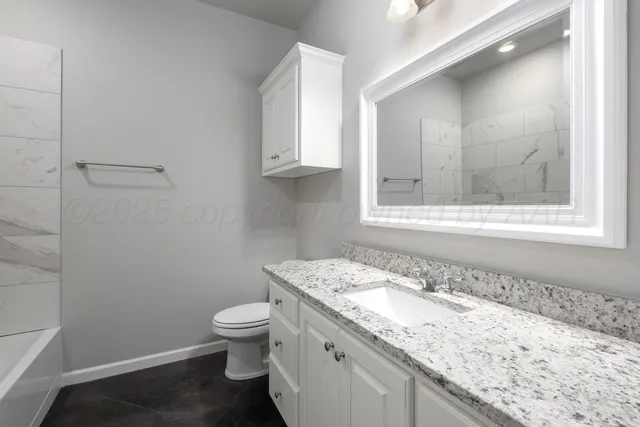 a bathroom with a granite countertop sink a toilet and a mirror