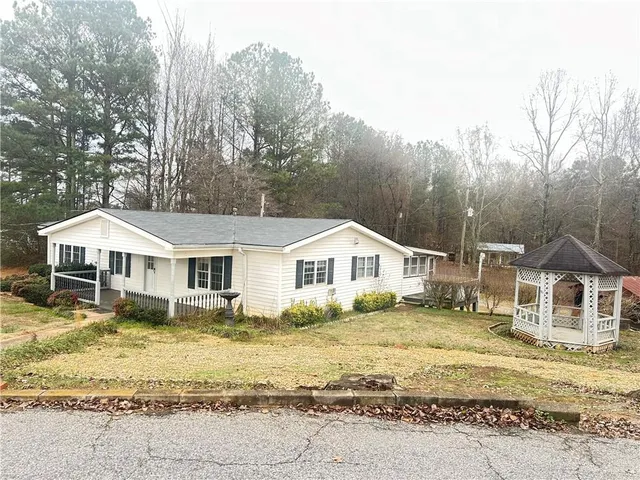 a front view of a house with a garden and trees