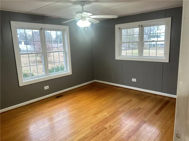 a view of empty room with wooden floor and fan