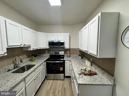 a kitchen with stainless steel appliances granite countertop a stove a sink dishwasher and a refrigerator with wooden cabinets