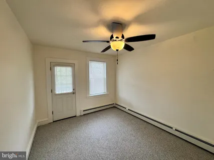 an empty room with a window and a fan