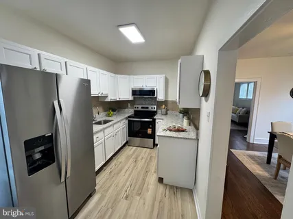 a kitchen with stainless steel appliances a refrigerator a sink a stove top oven a counter space and cabinets