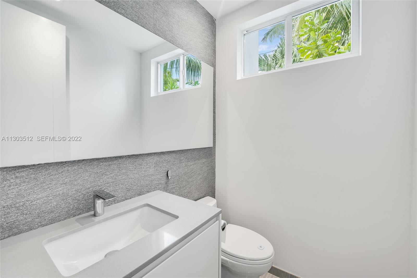 330 Fernwood Road, Unit 1 Key Biscayne, FL 33149 - Photo 12 of 29 a bathroom with a toilet sink and mirror