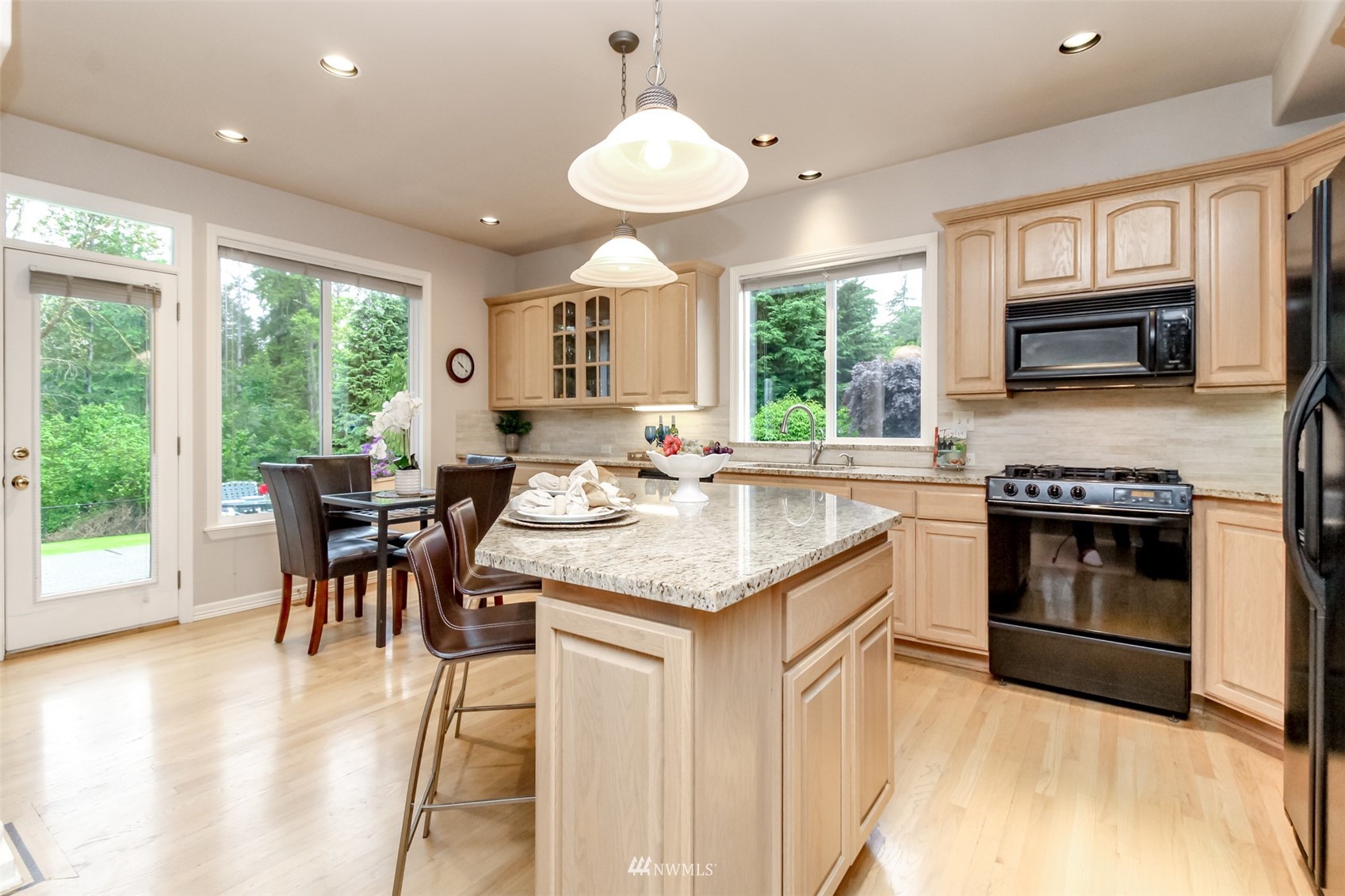 18910 3rd Street East Lake Tapps, WA 98391 - Photo 7 of 18 a kitchen with kitchen island granite countertop a stove a sink a dining table and chairs with wooden floor