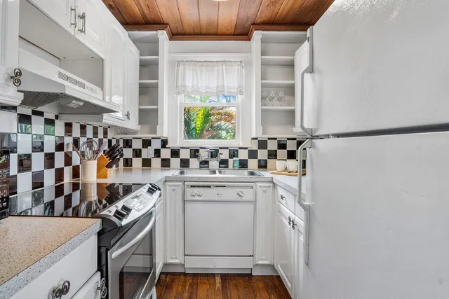 a kitchen with a sink a stove and white cabinets