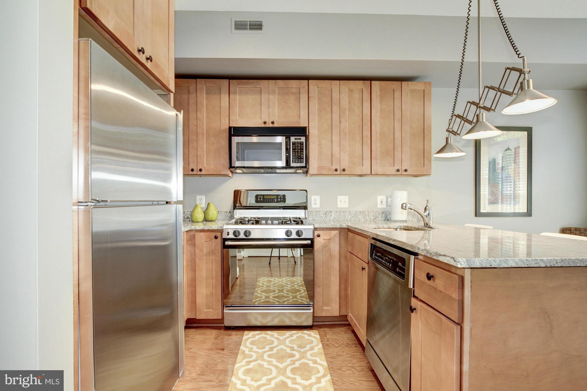 27 Logan Circle Northwest, Unit 1 Washington, DC 20005 - Photo 12 of 30 a kitchen with kitchen island granite countertop a sink stainless steel appliances and cabinets