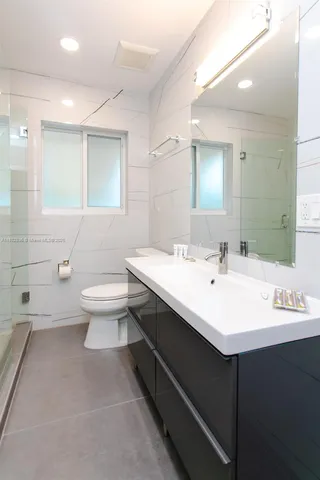 a bathroom with a double vanity sink toilet and mirror
