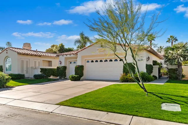 a view of a white house next to a yard with big trees