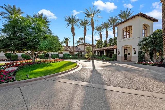 a view of a white house with a small yard and palm trees