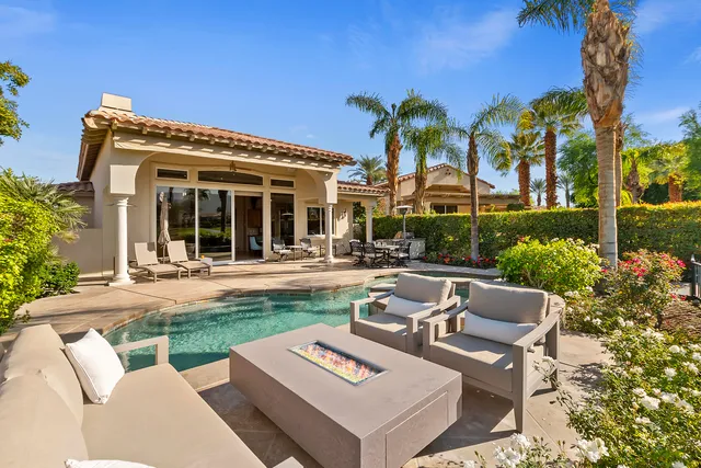 a view of a patio with couches table and chairs potted plants and palm tree
