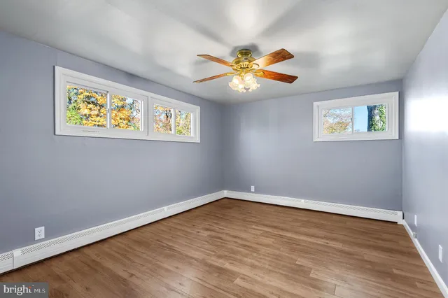 a view of an empty room with window and wooden floor