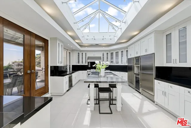 a large white kitchen with a large counter top appliances and cabinets