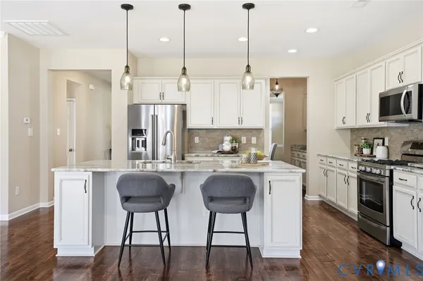 a kitchen with stainless steel appliances granite countertop a stove a sink a refrigerator a stove a dining table and chairs