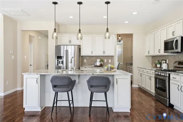 a kitchen with stainless steel appliances granite countertop a stove a sink a refrigerator a stove a dining table and chairs