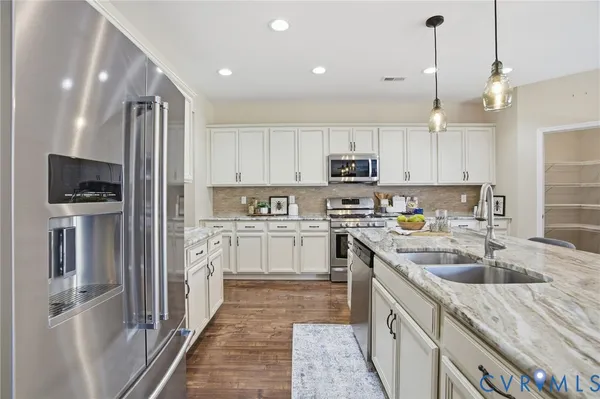 a kitchen with kitchen island granite countertop a sink refrigerator and microwave