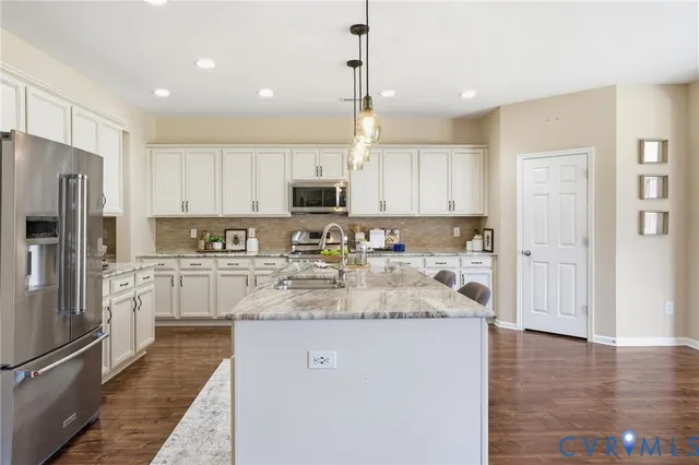 a kitchen with kitchen island granite countertop a refrigerator oven a sink and white cabinets