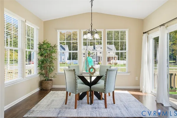 a dining room with furniture large windows and wooden floor