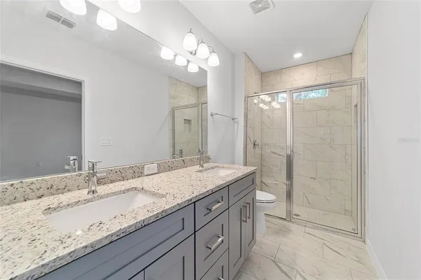 a bathroom with a granite countertop sink a mirror a vanity and shower
