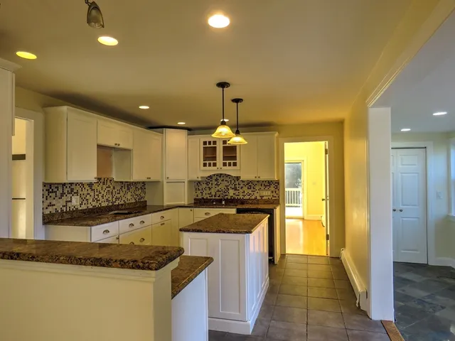 a kitchen with granite countertop kitchen island stainless steel appliances a sink stove and cabinets