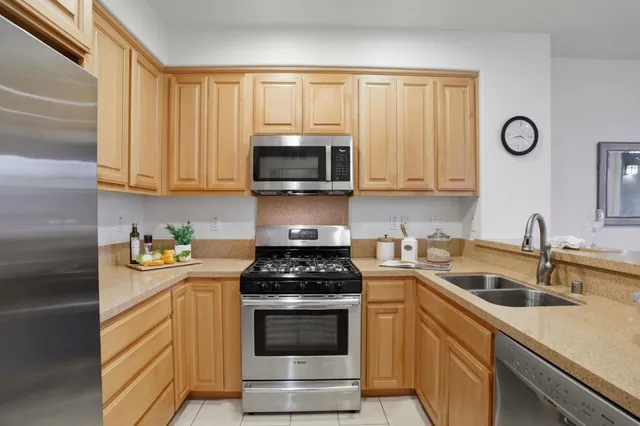 a kitchen with stainless steel appliances granite countertop a refrigerator a stove a sink and a microwave