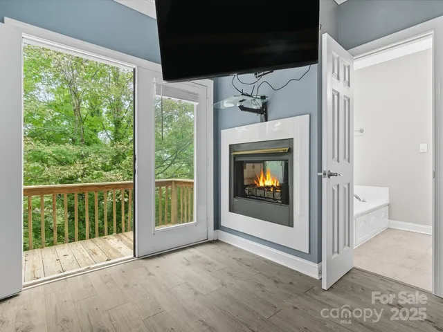 a view of an empty room with wooden floor and fireplace
