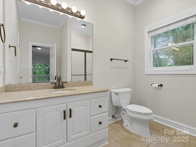 a bathroom with a granite countertop toilet sink and mirror