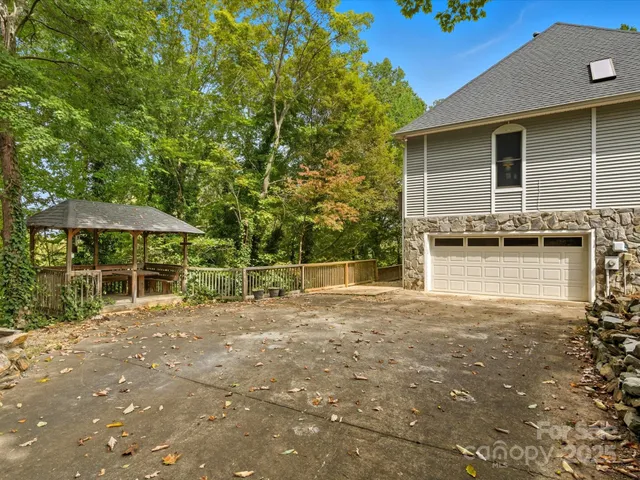 a backyard of a house with table and chairs under an umbrella