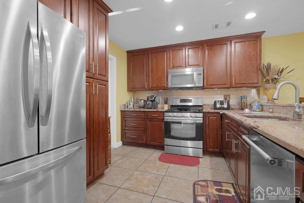 71 Winchester Way Somerset, NJ 08873 - Photo 7 of 24 a kitchen with granite countertop stainless steel appliances and wooden cabinets