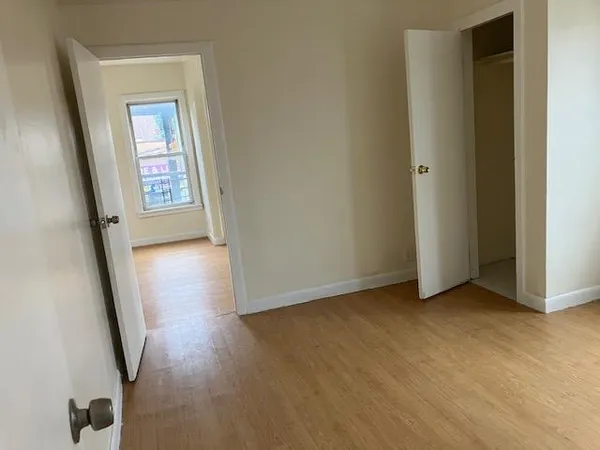 an empty room with wooden floor and mirror