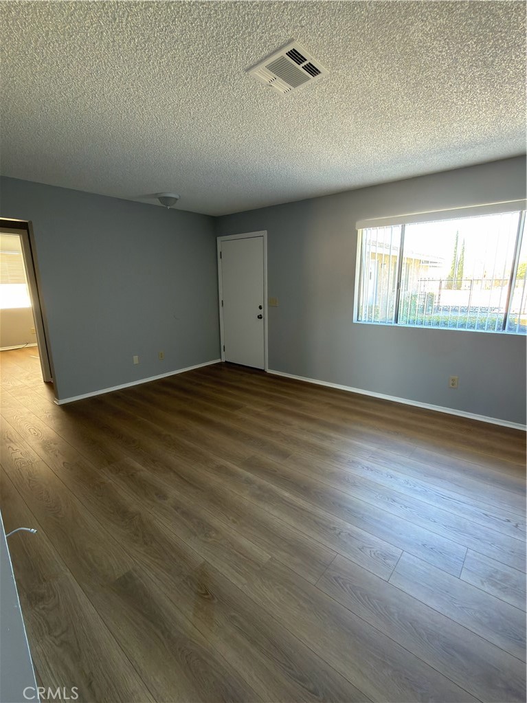 10547 Cochiti Road Apple Valley, CA 92308 - Photo 7 of 10 an empty room with wooden floor and windows